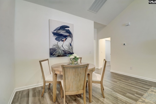 dining space featuring hardwood / wood-style floors and high vaulted ceiling