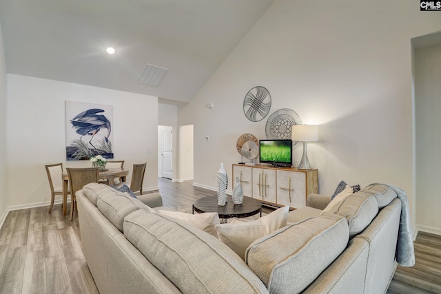 living room with hardwood / wood-style floors and high vaulted ceiling