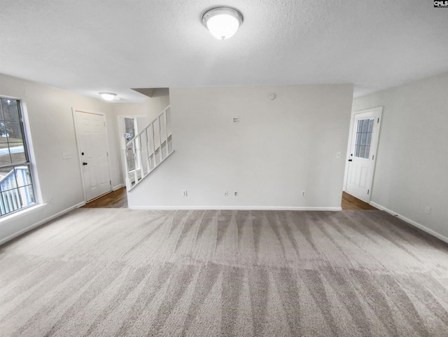 unfurnished living room featuring a textured ceiling and dark colored carpet