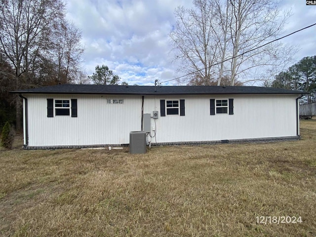 back of house featuring central AC unit and a lawn