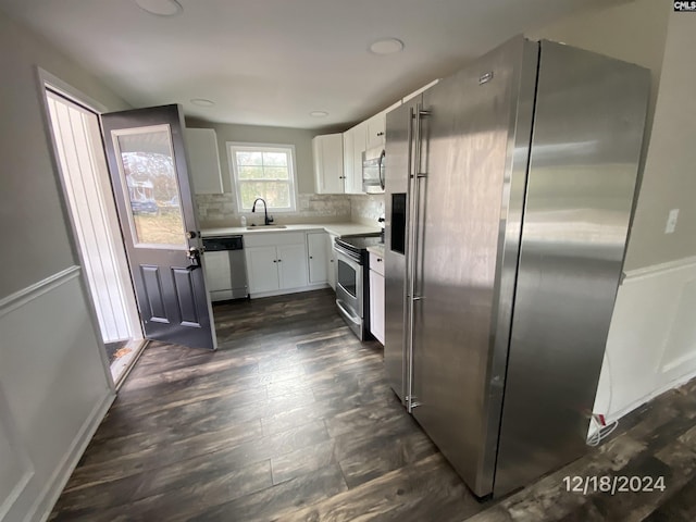 kitchen with appliances with stainless steel finishes, dark hardwood / wood-style flooring, tasteful backsplash, sink, and white cabinetry