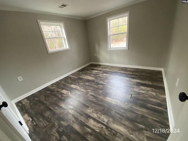 unfurnished room featuring ornamental molding and dark wood-type flooring