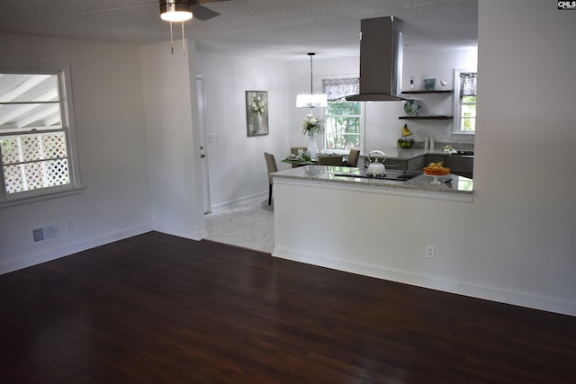 kitchen featuring hanging light fixtures, light hardwood / wood-style flooring, black electric cooktop, a textured ceiling, and island exhaust hood