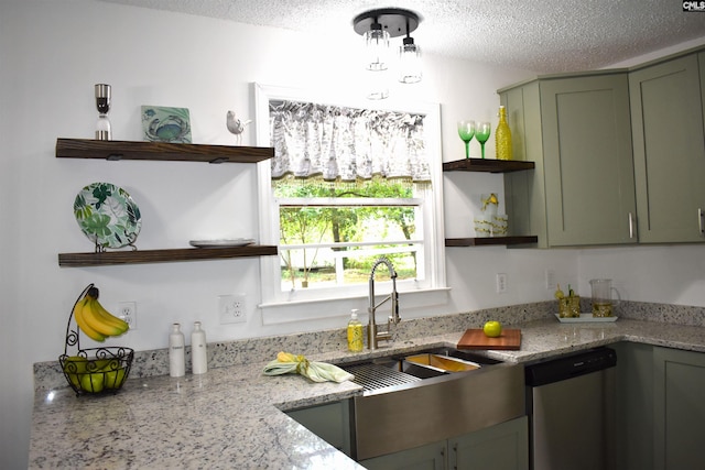 kitchen featuring light stone countertops, sink, green cabinets, stainless steel dishwasher, and a textured ceiling