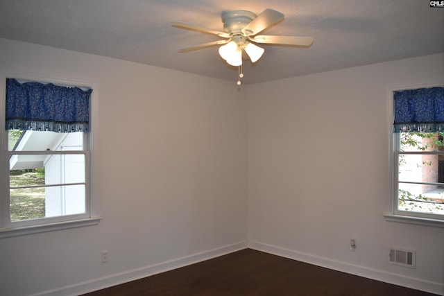 empty room with plenty of natural light, ceiling fan, and dark hardwood / wood-style floors