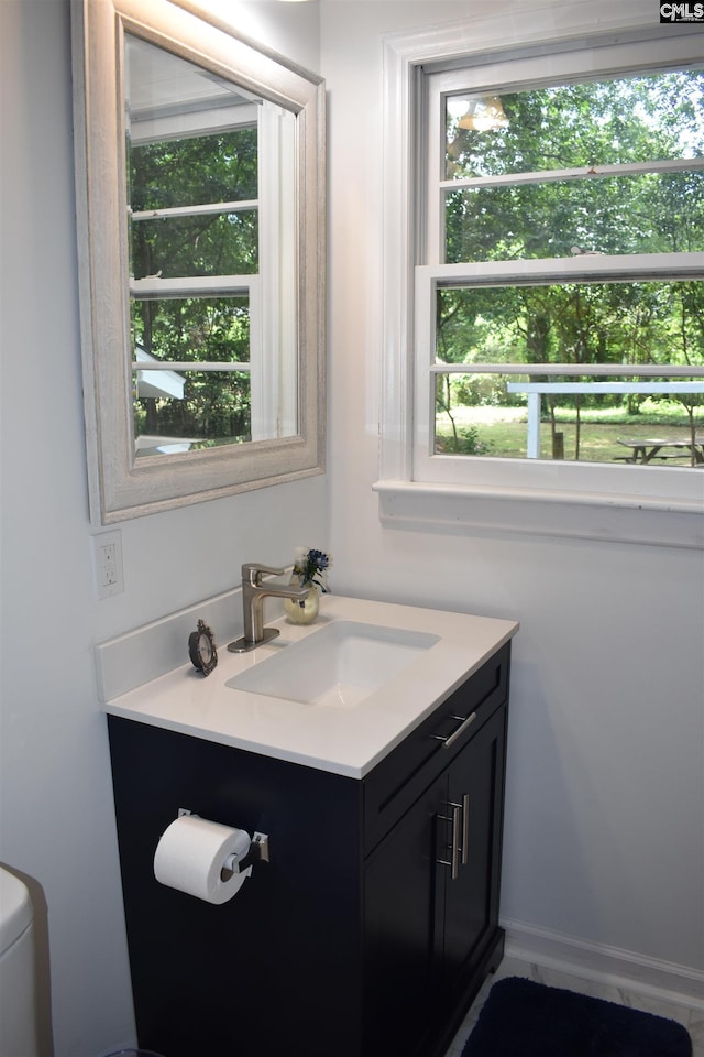 bathroom featuring vanity, a healthy amount of sunlight, and toilet