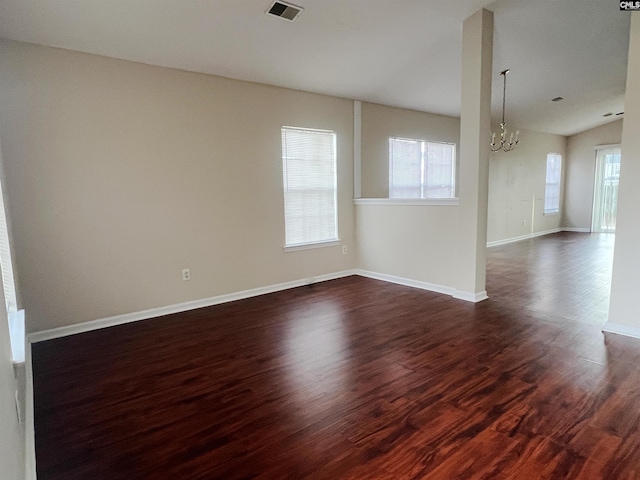 empty room with a chandelier and dark hardwood / wood-style floors