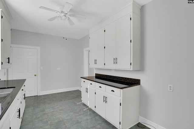 kitchen featuring dark stone countertops, ceiling fan, white cabinets, and light tile patterned floors