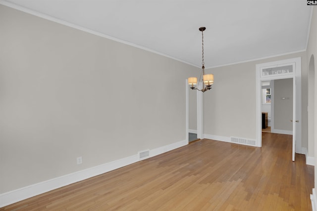 unfurnished room featuring a chandelier, hardwood / wood-style floors, and crown molding