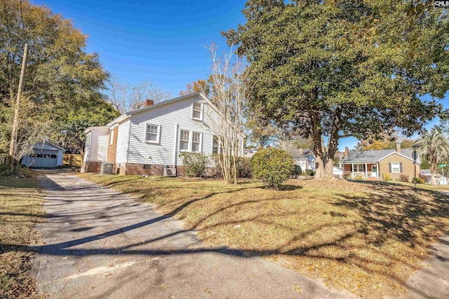 view of side of home with central AC, a yard, an outdoor structure, and a garage