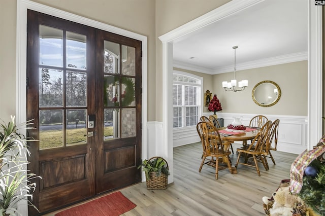 dining room with a notable chandelier, ornamental molding, light hardwood / wood-style flooring, and french doors