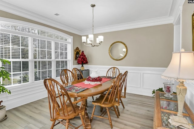 dining space featuring light hardwood / wood-style floors, an inviting chandelier, and crown molding