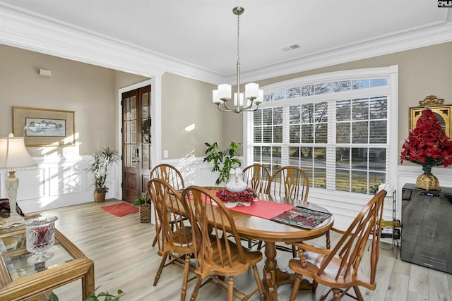 dining area featuring a notable chandelier, light hardwood / wood-style floors, and crown molding