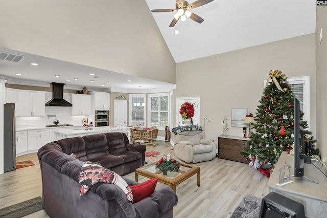 living room featuring ceiling fan, high vaulted ceiling, and light hardwood / wood-style flooring