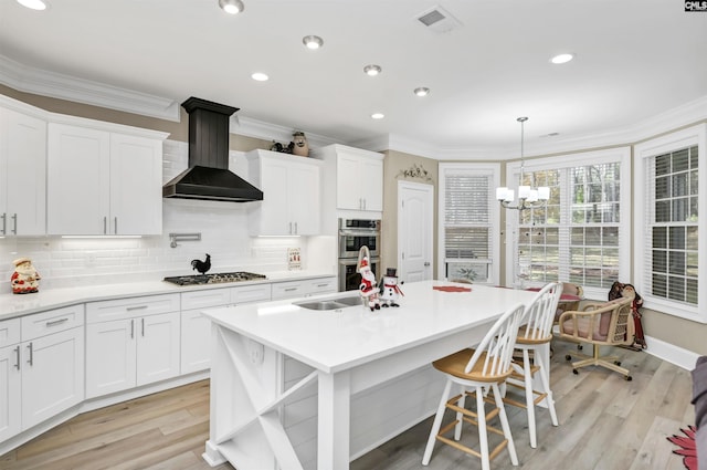 kitchen with white cabinetry, light hardwood / wood-style flooring, wall chimney exhaust hood, and stainless steel appliances