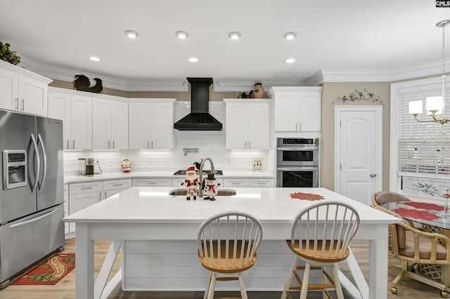 kitchen featuring appliances with stainless steel finishes, premium range hood, white cabinetry, and pendant lighting