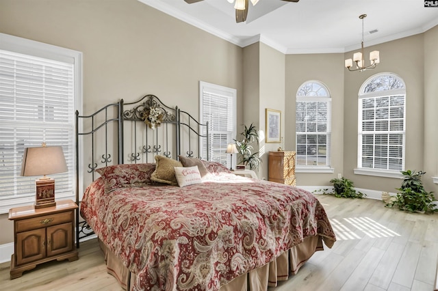 bedroom featuring crown molding, light hardwood / wood-style floors, and ceiling fan with notable chandelier