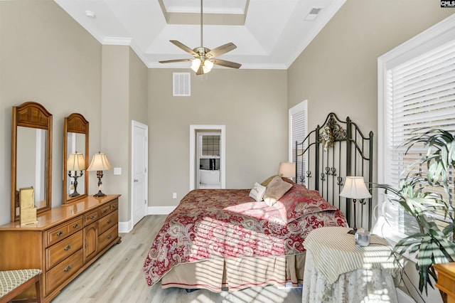 bedroom with ceiling fan, a raised ceiling, light wood-type flooring, and ornamental molding