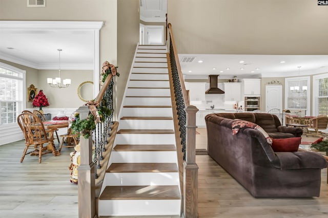 staircase featuring crown molding, hardwood / wood-style floors, and an inviting chandelier