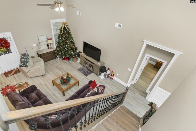 living room featuring ceiling fan, hardwood / wood-style floors, and a towering ceiling