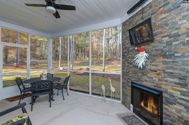 sunroom featuring plenty of natural light, ceiling fan, and an outdoor stone fireplace