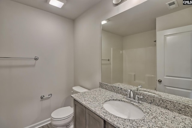 bathroom featuring vanity, toilet, and walk in shower