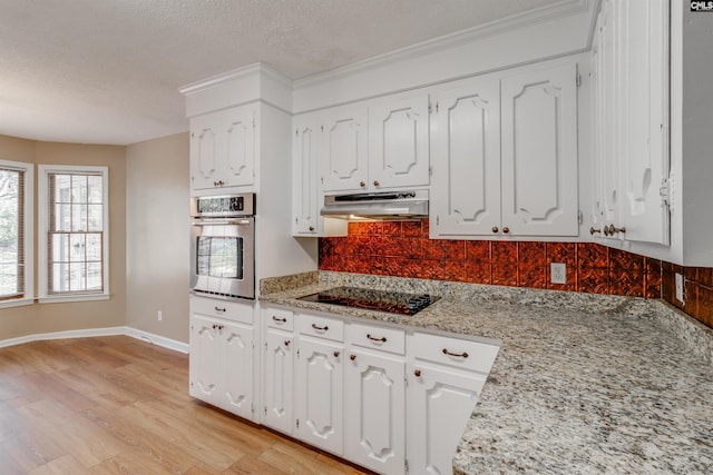 kitchen featuring light stone counters, stainless steel oven, white cabinets, and light hardwood / wood-style flooring