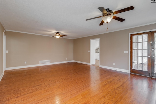 empty room featuring hardwood / wood-style floors, a textured ceiling, and ornamental molding