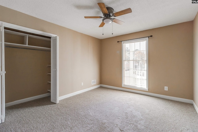 unfurnished bedroom featuring a textured ceiling, carpet floors, a closet, and ceiling fan