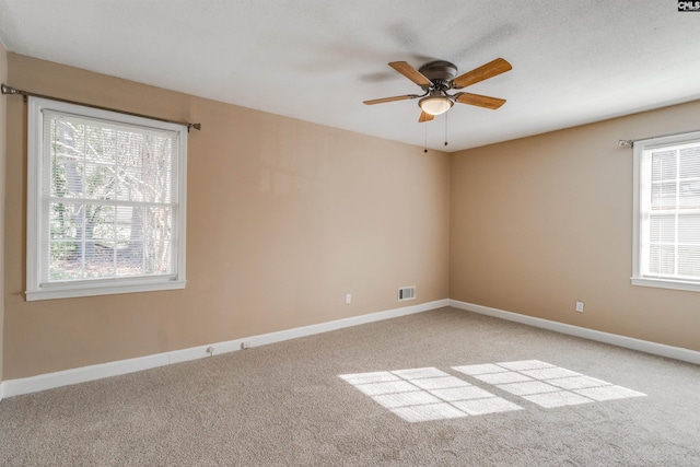 unfurnished room with carpet, a textured ceiling, a wealth of natural light, and ceiling fan