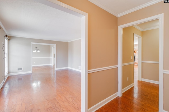 hallway featuring hardwood / wood-style flooring, an inviting chandelier, and crown molding