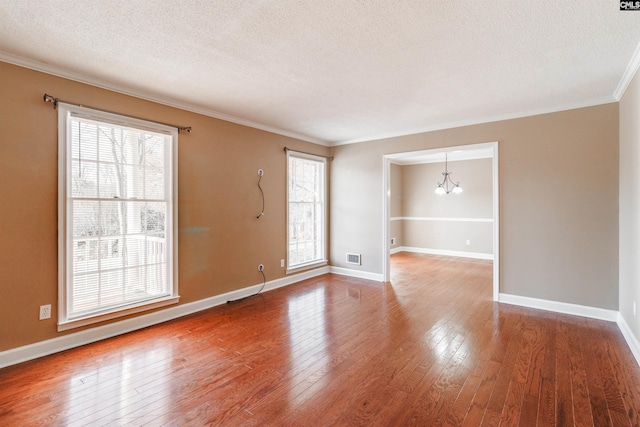 unfurnished room featuring a notable chandelier, wood-type flooring, a textured ceiling, and ornamental molding