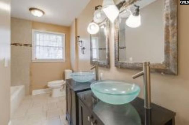 bathroom featuring toilet, a bath, vanity, and tile patterned floors