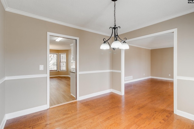 unfurnished room featuring hardwood / wood-style floors, a textured ceiling, crown molding, and an inviting chandelier