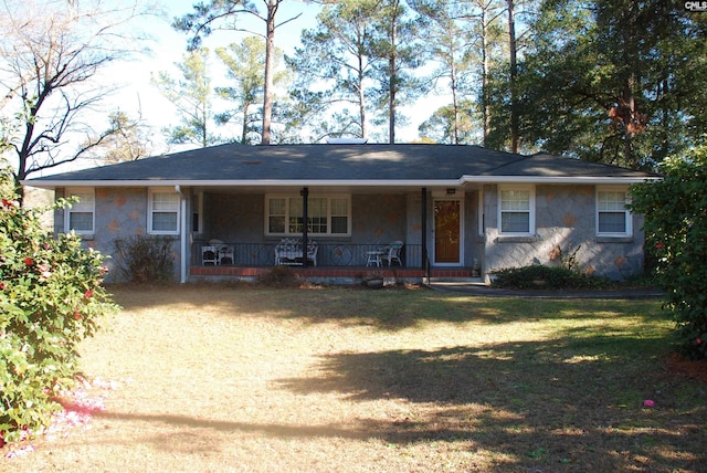 ranch-style home featuring covered porch and a front lawn