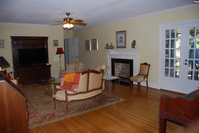 living room with hardwood / wood-style floors, a tile fireplace, french doors, ceiling fan, and ornamental molding