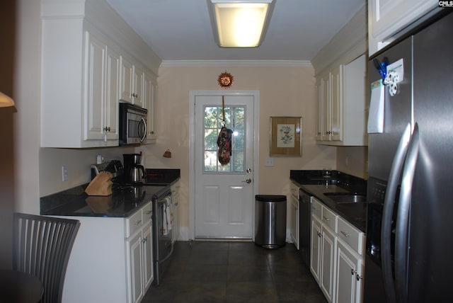 kitchen featuring white cabinetry, crown molding, dark tile patterned floors, and black appliances