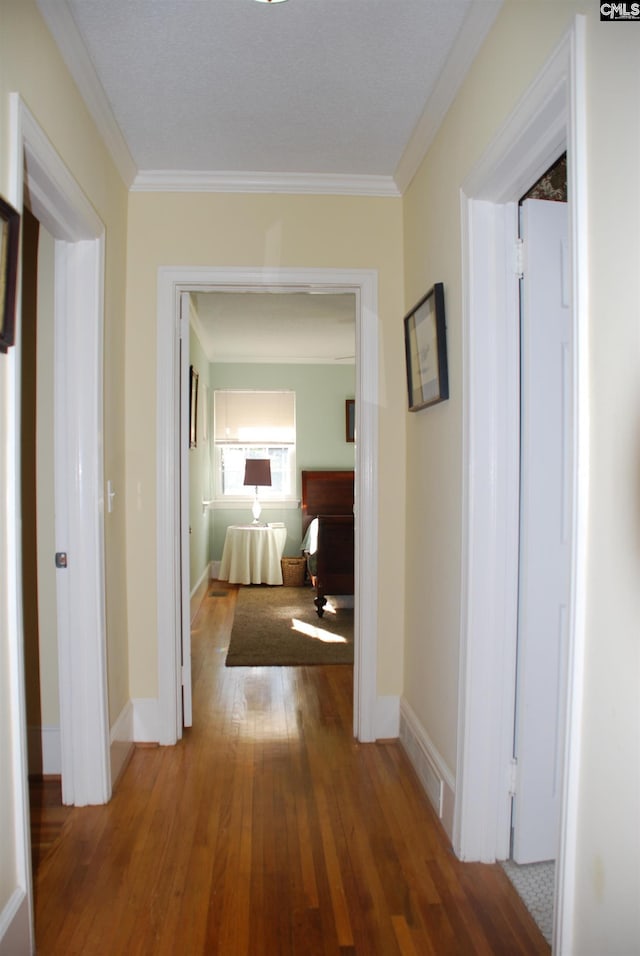 hall with wood-type flooring and crown molding