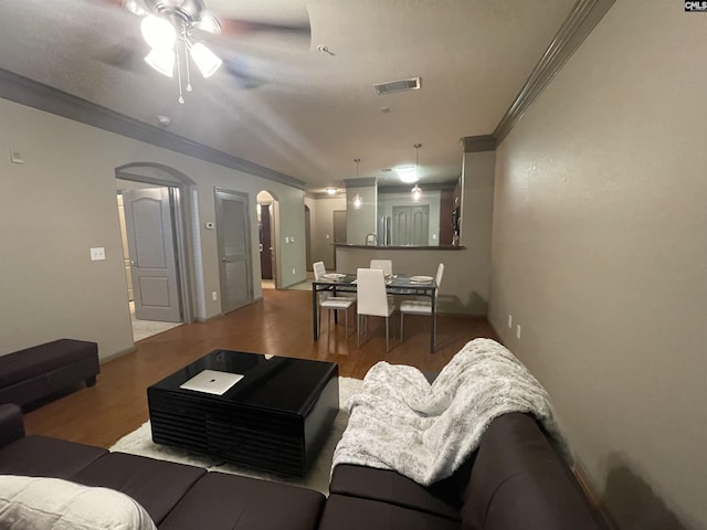 living room featuring wood-type flooring, ornamental molding, and ceiling fan