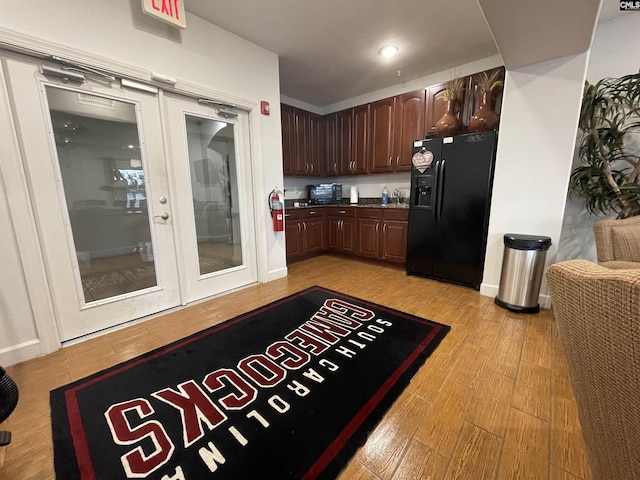 kitchen with dark brown cabinetry, black refrigerator with ice dispenser, french doors, and light wood-type flooring