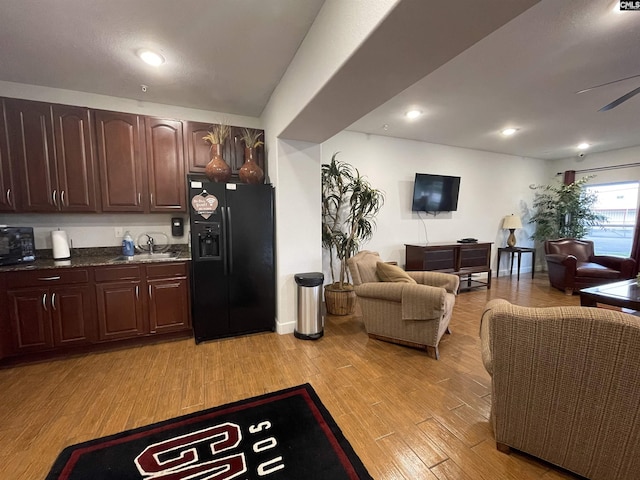 kitchen featuring black appliances, sink, dark brown cabinetry, ceiling fan, and light hardwood / wood-style flooring