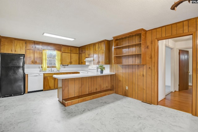 kitchen featuring white appliances, wooden walls, a textured ceiling, light hardwood / wood-style floors, and kitchen peninsula