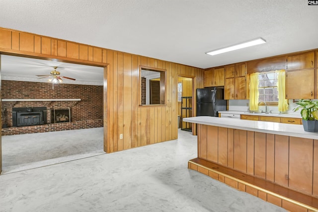 kitchen with wooden walls, black refrigerator, a textured ceiling, and sink