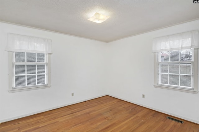 empty room with wood-type flooring and a textured ceiling