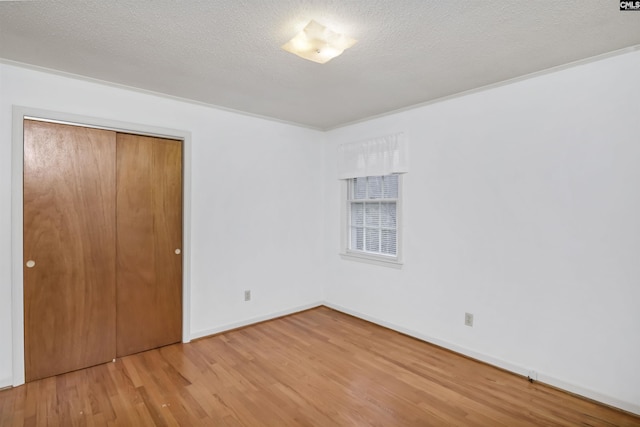 unfurnished bedroom with a textured ceiling, light hardwood / wood-style floors, and a closet