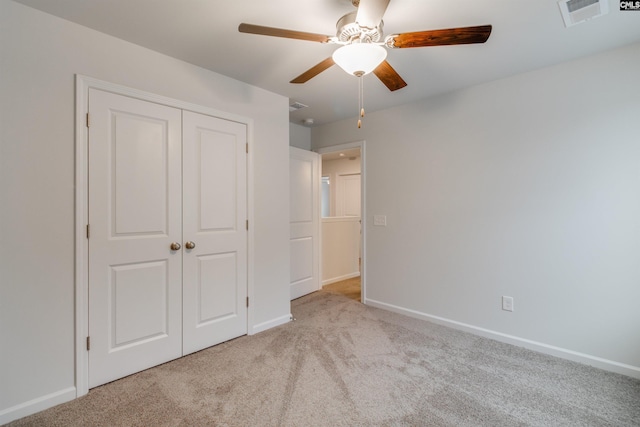 unfurnished bedroom with light carpet, a closet, and ceiling fan