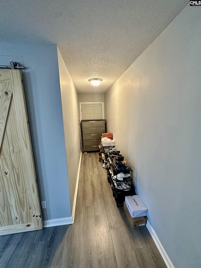 corridor with hardwood / wood-style floors, a barn door, and a textured ceiling