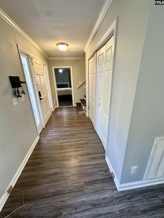 hall featuring ornamental molding, dark hardwood / wood-style floors, and a textured ceiling