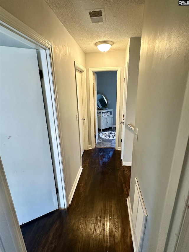 hall featuring dark wood-type flooring and a textured ceiling