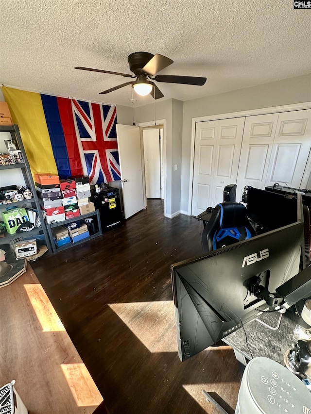 home office with ceiling fan, dark hardwood / wood-style floors, and a textured ceiling